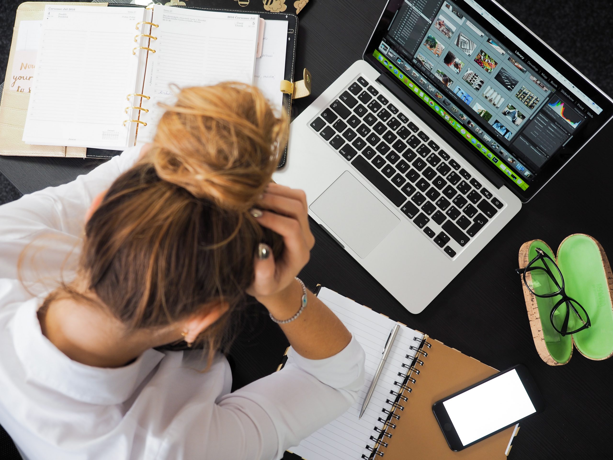 Kvinna framför laptop, med huvet i händerna